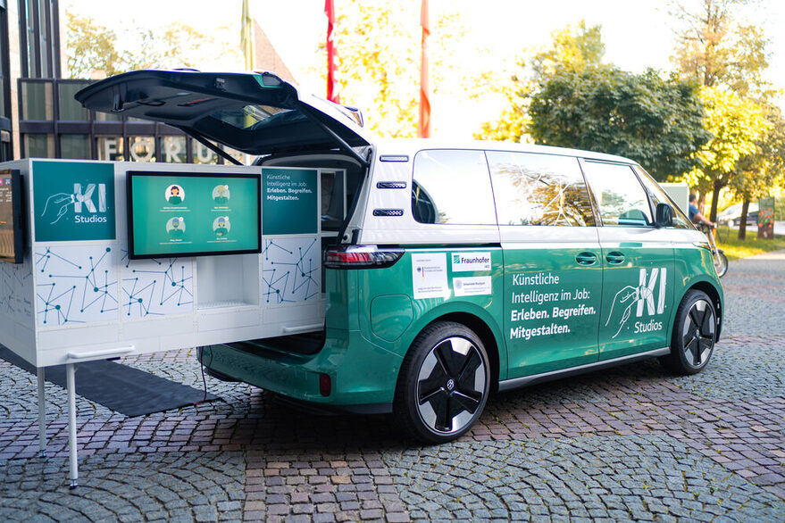 KI-Infomobil mit einem Auszug mit mehreren Monitoren.